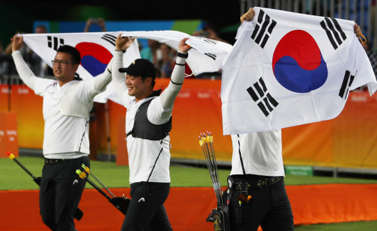 6일 오후(현지시간) 브라질 리우데자네이루 삼보드로모 경기장에서 열린 2016 리우올림픽 남자양궁 단체전 결승에서 미국을 꺾고 금메달을 차지한 한국 대표팀의 구본찬(오른쪽부터), 이승윤, 김우진이 태극기를 들고 관중에게 인사하고 있다.